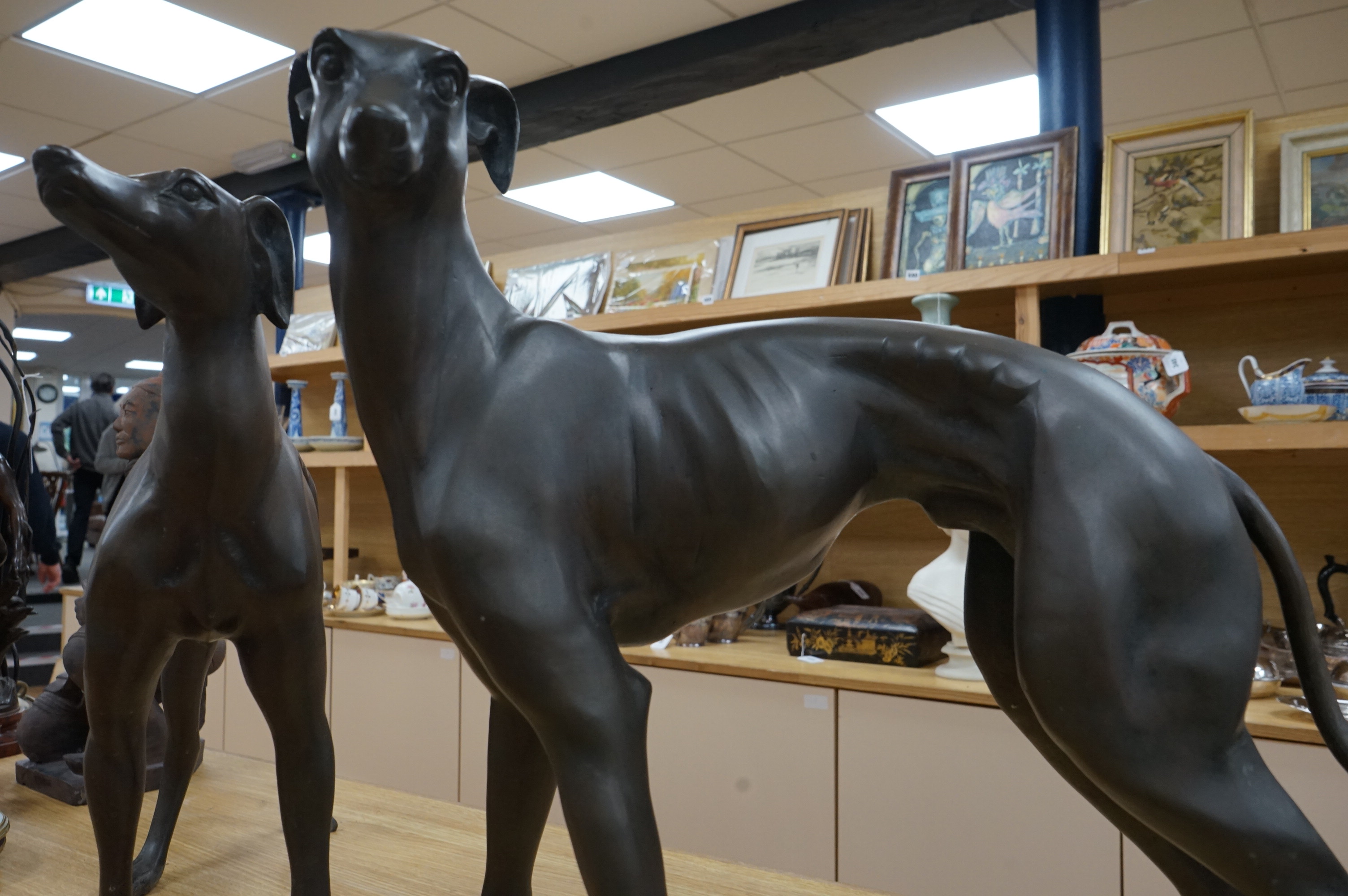 A pair of modern bronze greyhounds, approximately 66cm wide x 53cm high and 49cm wide x 57cm high. Condition - good